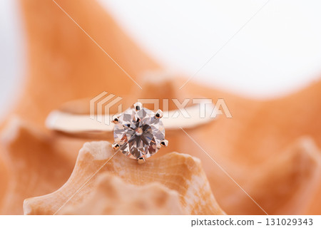 A gold and diamond ring is on top of a shell 131029343