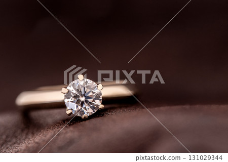 A diamond ring is sitting on a brown surface 131029344