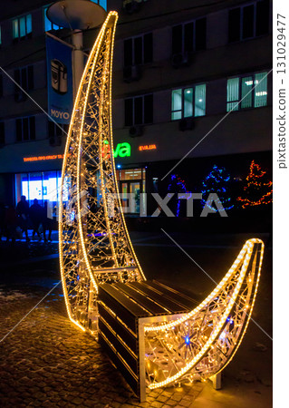 Illuminated crescent shaped bench in a park. Christmas urban decoration 131029477