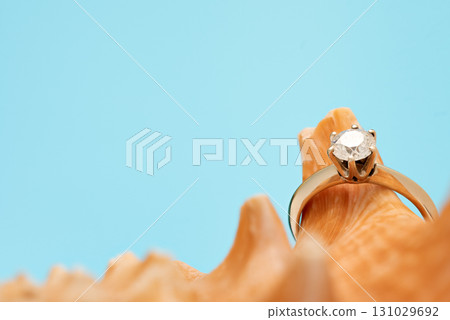 A gold and white diamond ring is on top of a seashell 131029692
