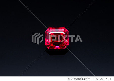 A red gemstone sits on a black surface 131029695