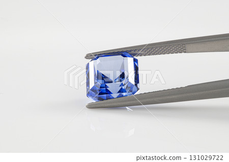 A blue gemstone is being held up by a metal tool A blue gemstone is being held up by a metal tool 131029722