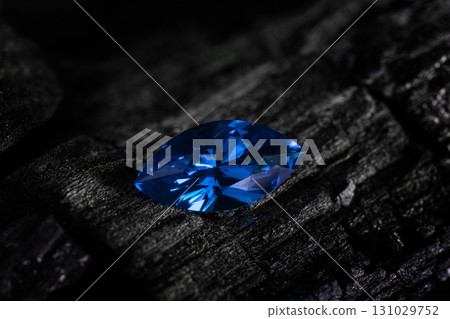 A blue gemstone is sitting on a black rock A blue gemstone is sitting on a black rock 131029752