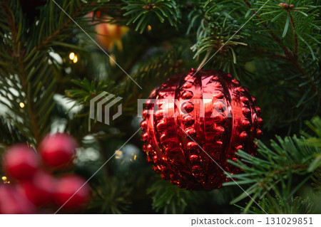 Christmas tree with red ball and lights garland. Xmas card. Winter festive holiday. Outdoors. Close up. 131029851