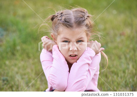 Caucasian girl child with braided hair showing defiant expression in pink shirt Caucasian girl child with braided hair showing defiant expression in pink shirt 131031375