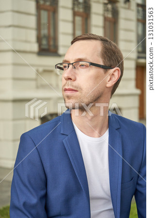Young caucasian male in blue blazer and glasses looking away outside historical Young caucasian male in blue blazer and glasses looking away outside historical 131031563