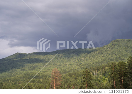 Dramatic sky over lush green forested hills with approaching storm clouds Dramatic sky over lush green forested hills with approaching storm clouds 131031575