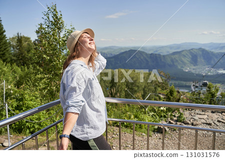 Young caucasian female enjoying mountain view in summer, wearing hat and striped 131031576