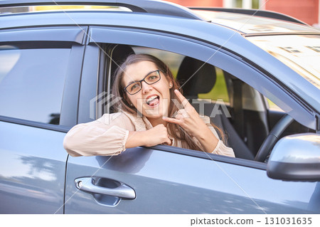 Caucasian female adult making rock gesture in car showing playful expression Caucasian female adult making rock gesture in car showing playful expression 131031635