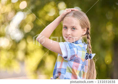 Caucasian young girl with braided hair in plaid dress outdoors in sunlit 131031638