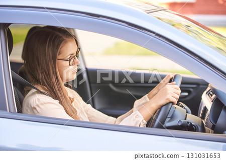 Caucasian young adult female driving car with focused expression in daylight 131031653