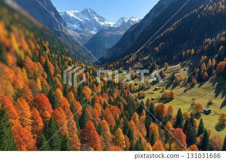 Idyllic mountain valley in autumn with colorful forest, wooden cabins, green meadows and snow-covered peaks in background. Concept of peaceful nature landscape, fall season scenery, rural getaway 131031686