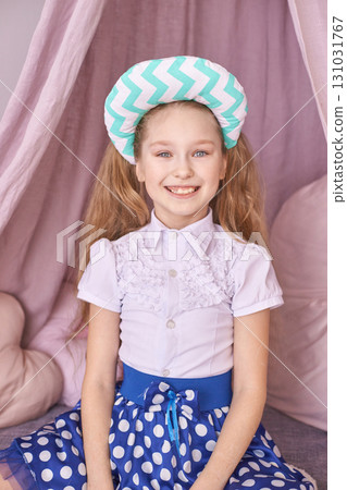 Smiling caucasian female child in polka dot skirt with chevron pillow and pink 131031767