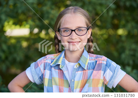 Smiling caucasian female child with glasses in plaid shirt outdoors in nature 131031780