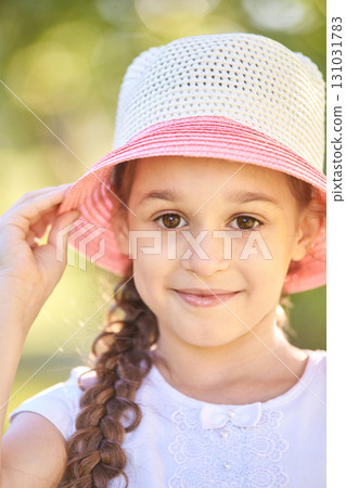Smiling caucasian young girl in pink and white hat outdoors on a sunny day Smiling caucasian young girl in pink and white hat outdoors on a sunny day 131031783