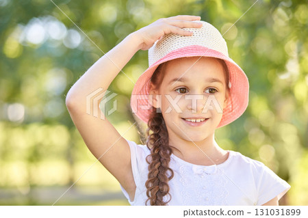 Smiling caucasian young girl with braid wearing straw hat in sunny park 131031899