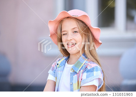 Happy caucasian female child with long hair and pink hat winking and sticking Happy caucasian female child with long hair and pink hat winking and sticking 131031903