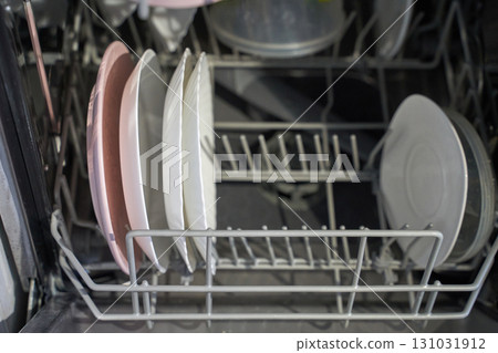 Clean dishes in open dishwasher with neatly arranged plates and bowls 131031912