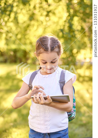 Young caucasian girl using tablet outdoors in sunlit park Young caucasian girl using tablet outdoors in sunlit park 131031917
