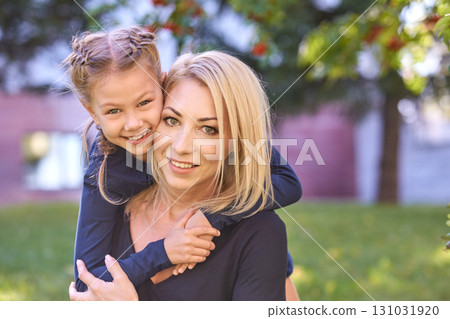 Smiling caucasian mother with child enjoying outdoors in sunny park with trees Smiling caucasian mother with child enjoying outdoors in sunny park with trees 131031920