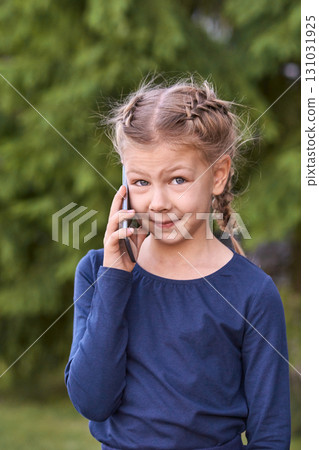 Caucasian female child with braided hair talking on phone outdoors in blue 131031925