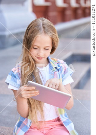 Young caucasian female child engaged with tablet in outdoor urban setting 131032271