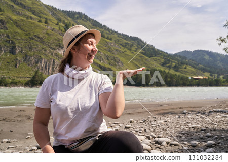 Smiling caucasian young female enjoying nature by mountain river on a sunny day Smiling caucasian young female enjoying nature by mountain river on a sunny day 131032284