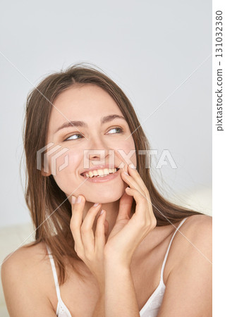 Smiling young caucasian female with long brown hair in white tank top 131032380