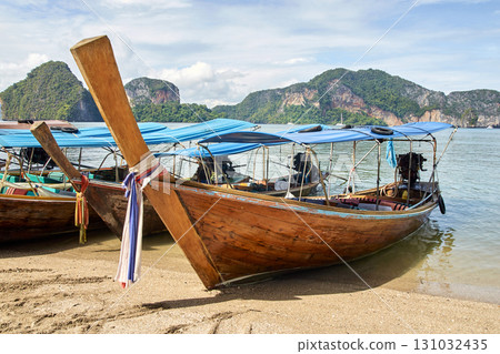 Traditional longtail boats on sandy beach with scenic mountain view in tropical Traditional longtail boats on sandy beach with scenic mountain view in tropical 131032435
