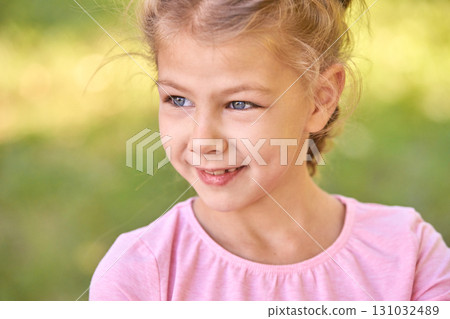 Smiling caucasian female child with braided hair in pink shirt outdoors 131032489