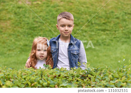 Caucasian young male and child female siblings outdoors in green park 131032531