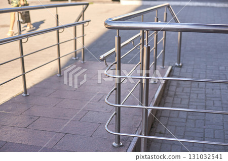 Modern metal railings and ramp in urban setting with stone and concrete paving 131032541