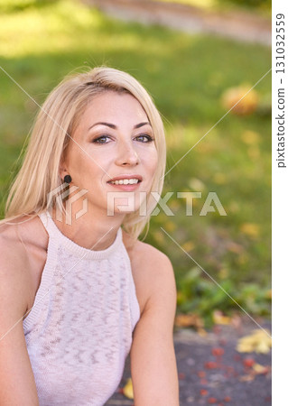 Smiling caucasian female adult relaxing outdoors in sunlit park with autumn 131032559