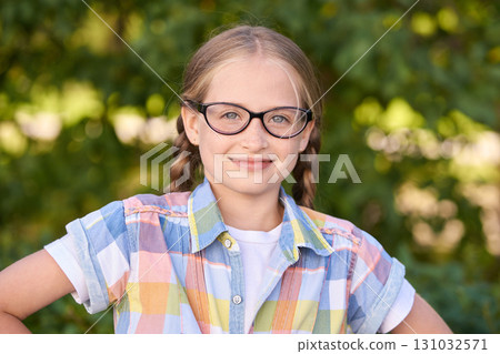 Smiling caucasian young girl with glasses in plaid shirt posing outdoors Smiling caucasian young girl with glasses in plaid shirt posing outdoors 131032571