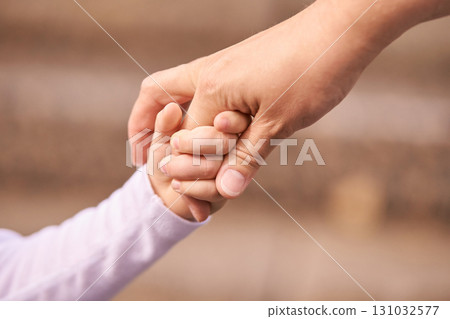 Tender bond between adult and child hands symbolizing care and connection 131032577