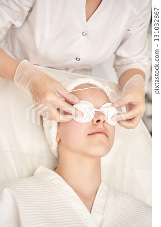 Young caucasian female receiving spa facial treatment with eye pads at wellness Young caucasian female receiving spa facial treatment with eye pads at wellness 131032867