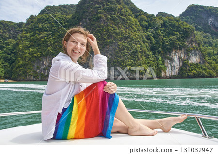 Caucasian young female smiling on boat in tropical waters with rainbow skirt Caucasian young female smiling on boat in tropical waters with rainbow skirt 131032947
