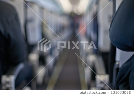 Blurred interior view of airplane cabin with rows of seats and passengers 131033058