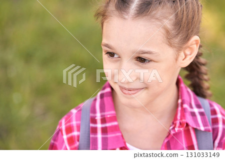 Smiling caucasian young girl in pink plaid shirt enjoying outdoors with braided 131033149