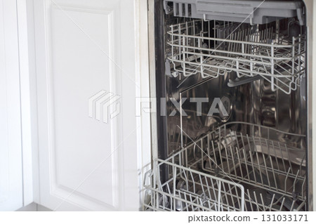 Open dishwasher with empty racks in a modern kitchen interior showing details 131033171