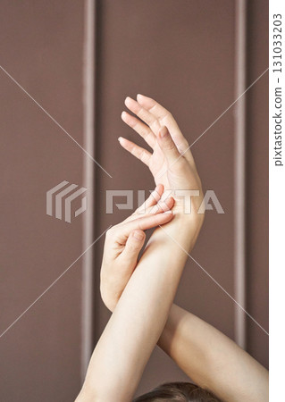 Close-up of female hands with graceful pose against neutral brown background 131033203