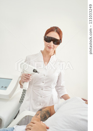 Female asian adult performing laser treatment in modern clinic environment Female asian adult performing laser treatment in modern clinic environment 131033249