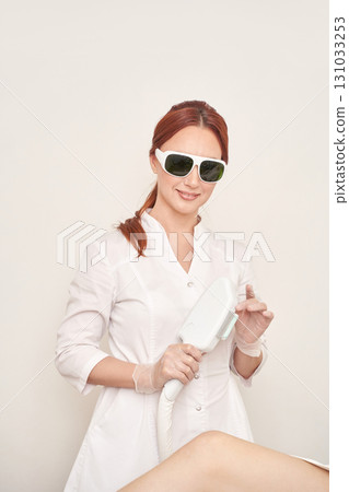 Female caucasian adult performing laser hair removal procedure in medical 131033253