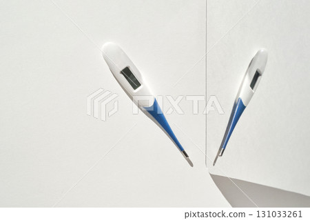Two digital thermometers on white surface displaying temperature measurement Two digital thermometers on white surface displaying temperature measurement 131033261
