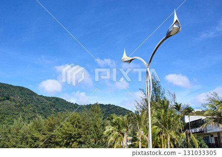 Modern metallic sculpture with blue sky and lush greenery in outdoor landscape 131033305
