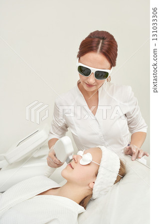 Female asian adult dermatologist performing laser skin treatment on young 131033306