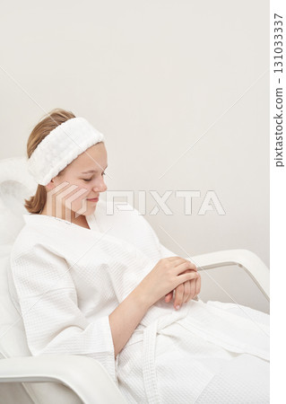 Young caucasian female relaxing in spa with white bathrobe and headband 131033337