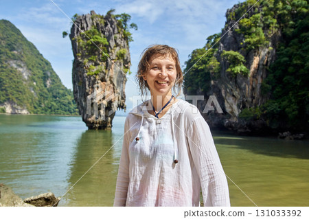 Female traveler smiling in front of limestone islands in sunny tropical waters Female traveler smiling in front of limestone islands in sunny tropical waters 131033392