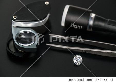A diamond is on a table with a magnifying glass and a light A diamond is on a table with a magnifying glass and a light 131033481