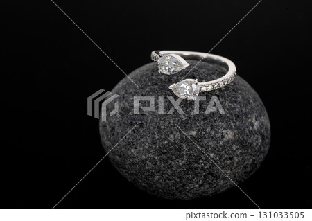 A ring with two diamonds on it is sitting on a rock A ring with two diamonds on it is sitting on a rock 131033505